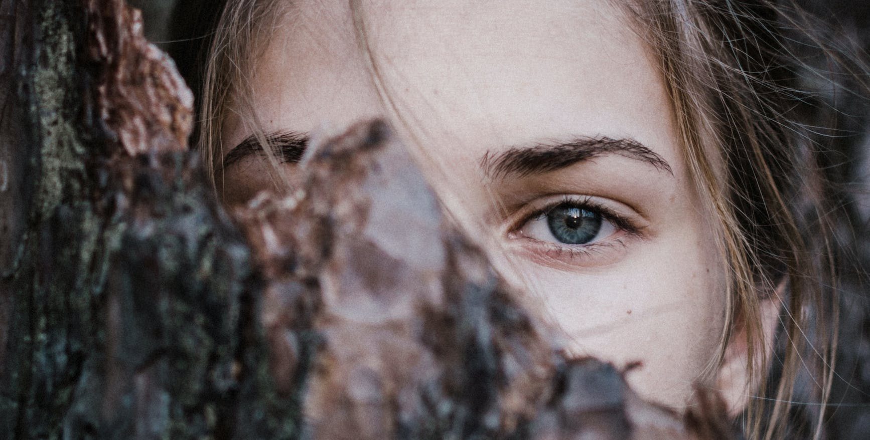 calm woman behind tree bark in park