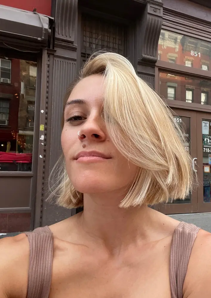 Guest standing outside with a bobbed haircut and all over blonde highlights varying depth