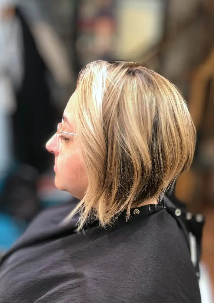 Guest seated in salon with bobbed hair and blonde balayage
